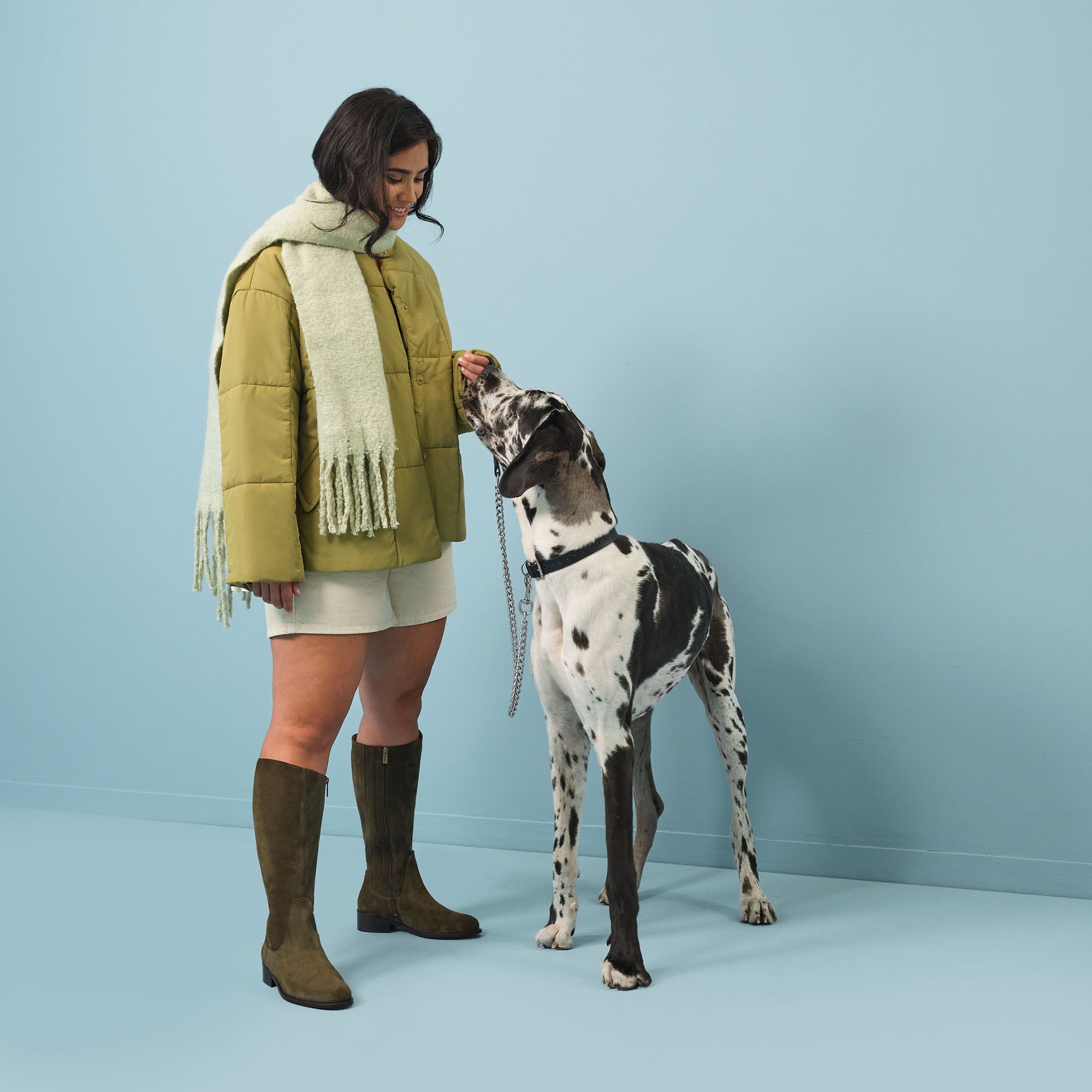 woman wearing wide calf forest green suede boots standing next to a dog