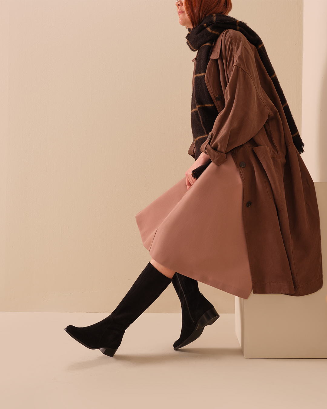 Woman Sitting Down Wearing A Pink Skirt And Haltham Tall Black Suede Knee High Boots DuoBoots