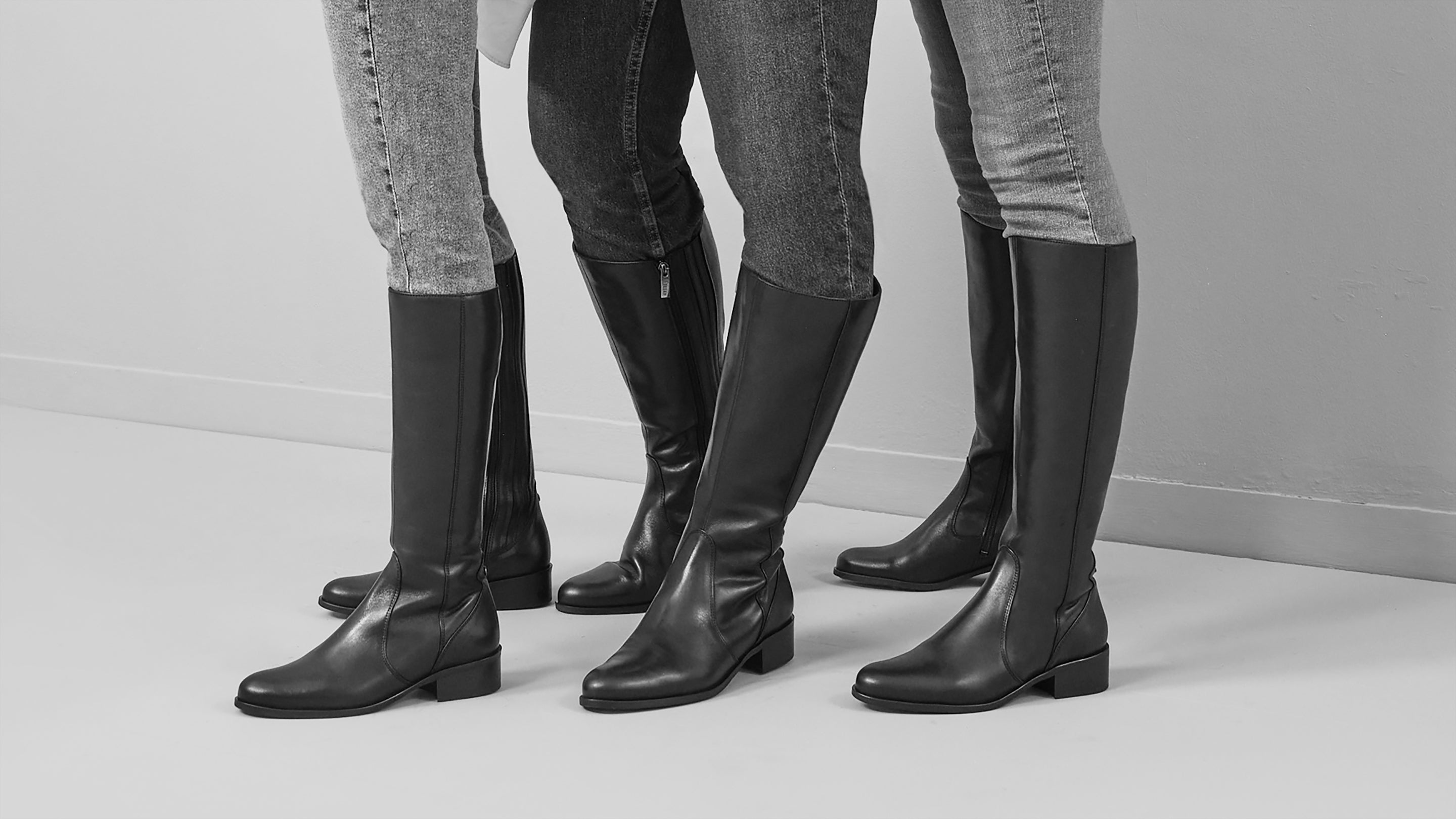 three women wearing black leather knee high flat boots