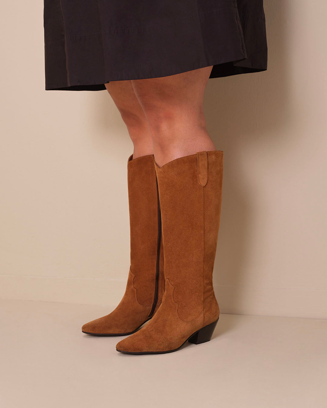 woman wearing knee high western style cowboy tan suede heeled boots