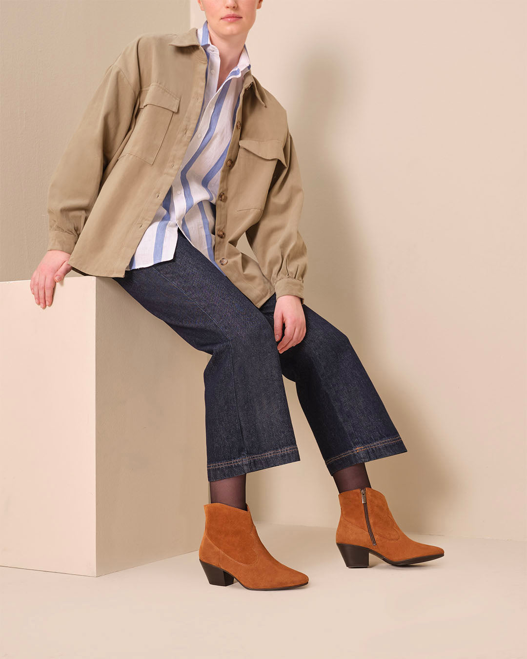 woman wearing cowboy western style tan suede heeled ankle boots