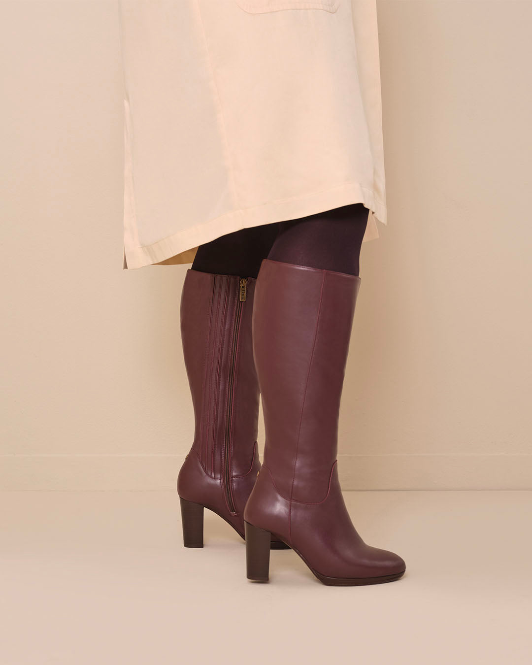 woman wearing knee high wide calf burgundy heeled boots