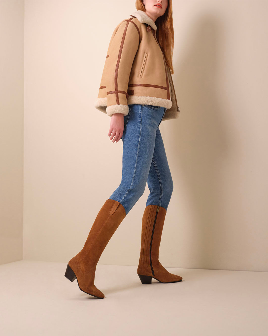 woman wearing knee high narrow calf cowboy style tan suede heeled boots