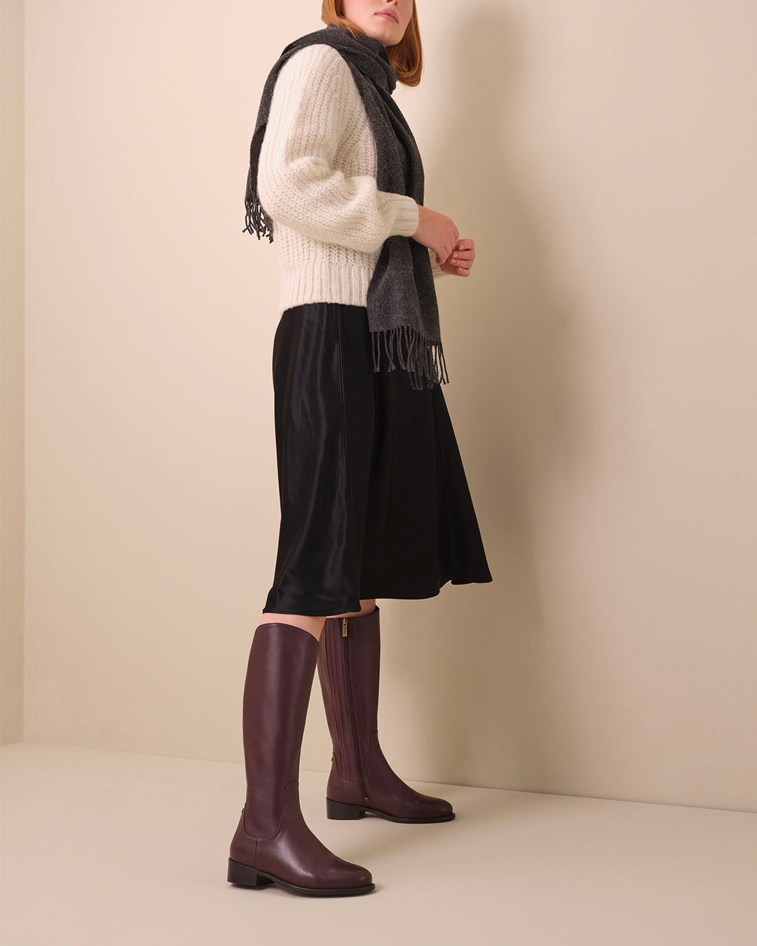 woman wearing knee high narrow calf burgundy leather flat boots